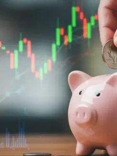 Hand placing coin into piggy bank amidst financial charts, symbolizing savings and economic impact
