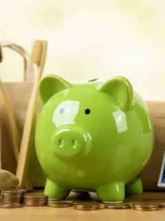 Green piggy bank surrounded by sustainable items, representing financial savings through eco-friendly living.