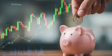 Hand placing coin into piggy bank amidst financial charts, symbolizing savings and economic impact